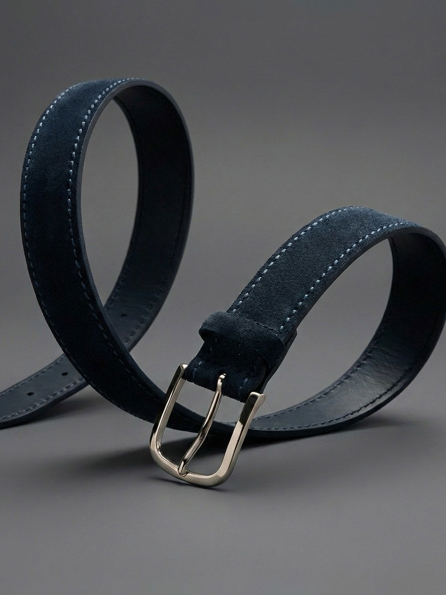 Navy blue suede belt with light blue stitching and a silver metal buckle displayed on a gray background.