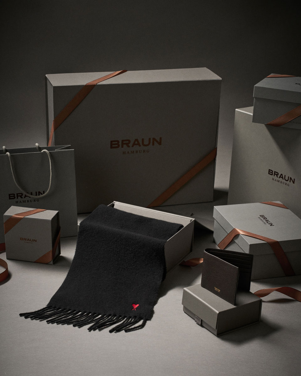 Geschenkboxen und -tüten von Braun Hamburg mit braunen Schleifen, schwarzem Schal und braunem Lederportemonnaie.