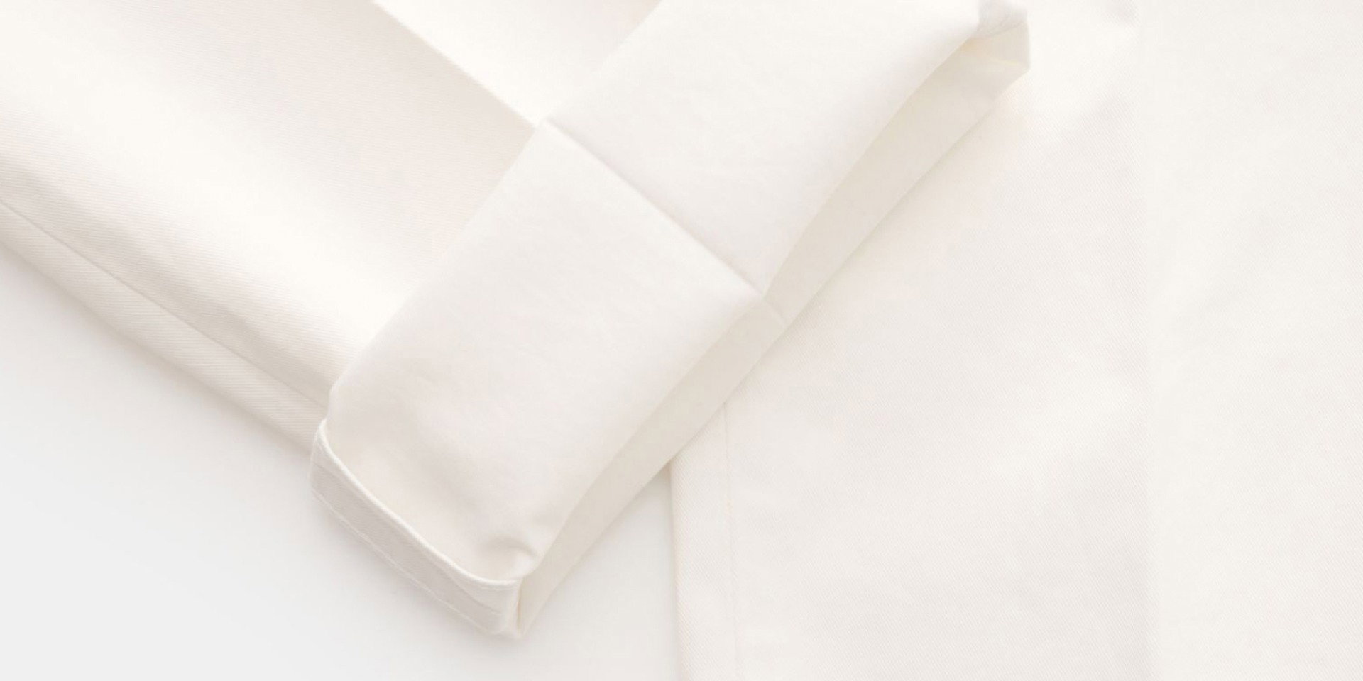 Weißes, fein strukturiertes Hemd mit detailreicher, sauber gefalteter Manschette und glatter Stoffoberfläche.