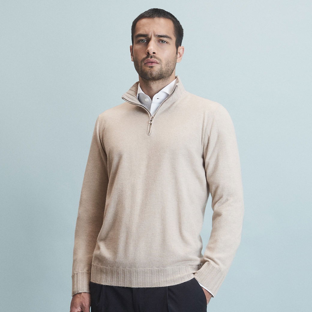 Anschnitt eines Herrn mit cremefarbenem Troyer über einem weißen Hemd