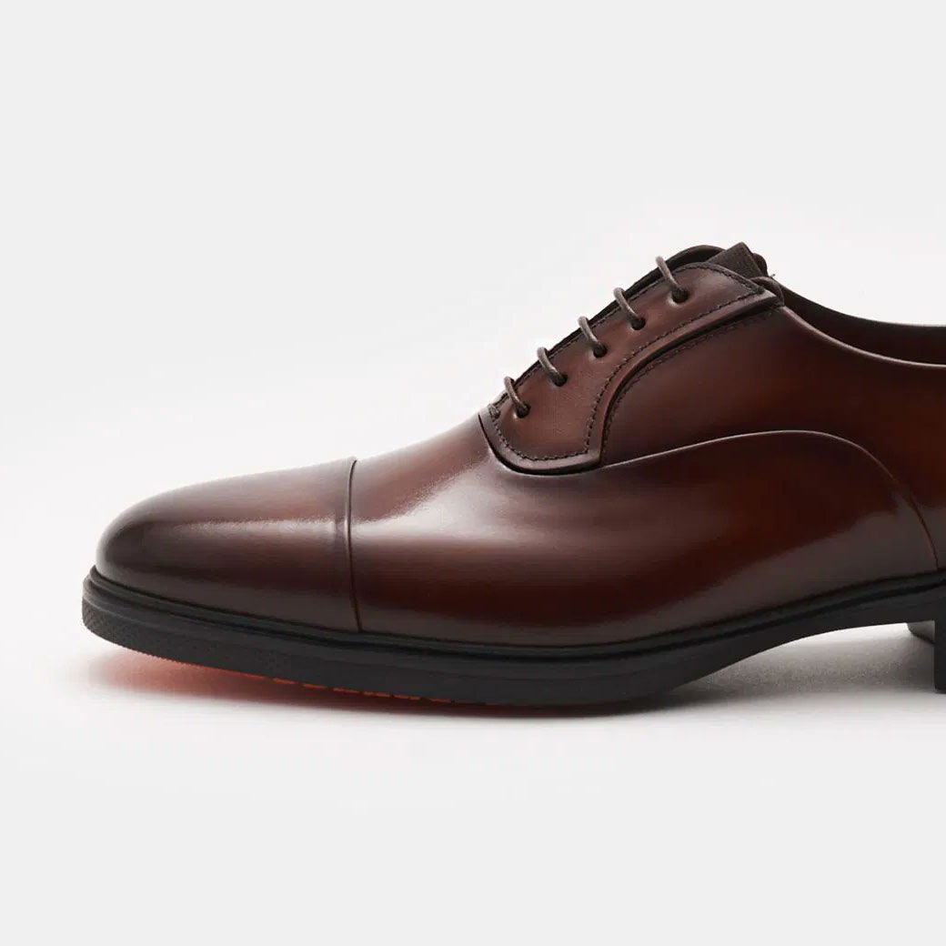 Brauner Herrenschuh Oxford aus Glattleder, seitliche Ansicht, Schnürung, eleganter Schuh mit glatter, glänzender Oberfläche. Brauner Herrenschuh Oxford aus Glattleder, seitliche Ansicht, Schnürung, eleganter Schuh mit glatter, glänzender Oberfläche.