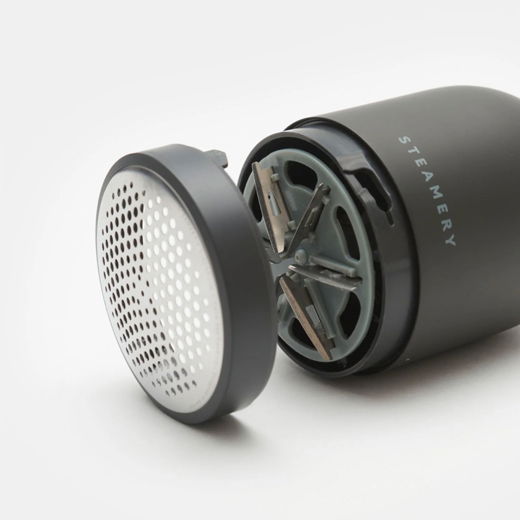 Anthrazitfarbener Stoffrasierer mit abgenommenem Metallrasierkopf und sichtbaren Klingen auf weißem Hintergrund. Anthrazitfarbener Stoffrasierer mit abgenommenem Metallrasierkopf und sichtbaren Klingen auf weißem Hintergrund.