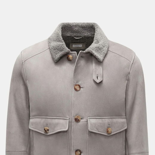 Hellgrauer Herren-Lammfell-Blouson mit Fellkragen, zwei Pattentaschen und braunen Hornknöpfen, Frontansicht. Hellgrauer Herren-Lammfell-Blouson mit Fellkragen, zwei Pattentaschen und braunen Hornknöpfen, Frontansicht.