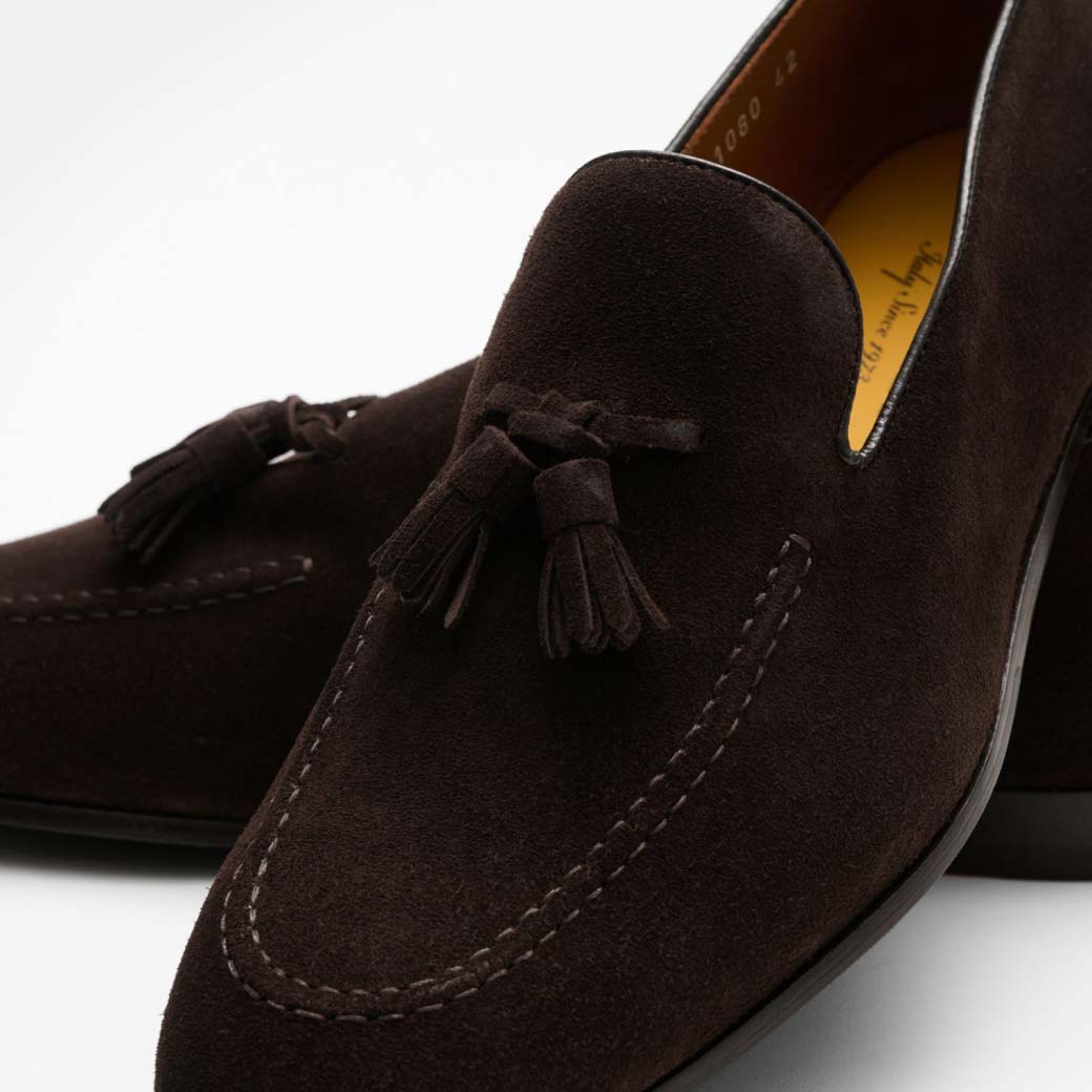 Dunkelbrauner Herren-Tasselloafer aus Veloursleder mit Quasten, feiner Naht und gelblich-brauner Innensohle, Nahaufnahme.