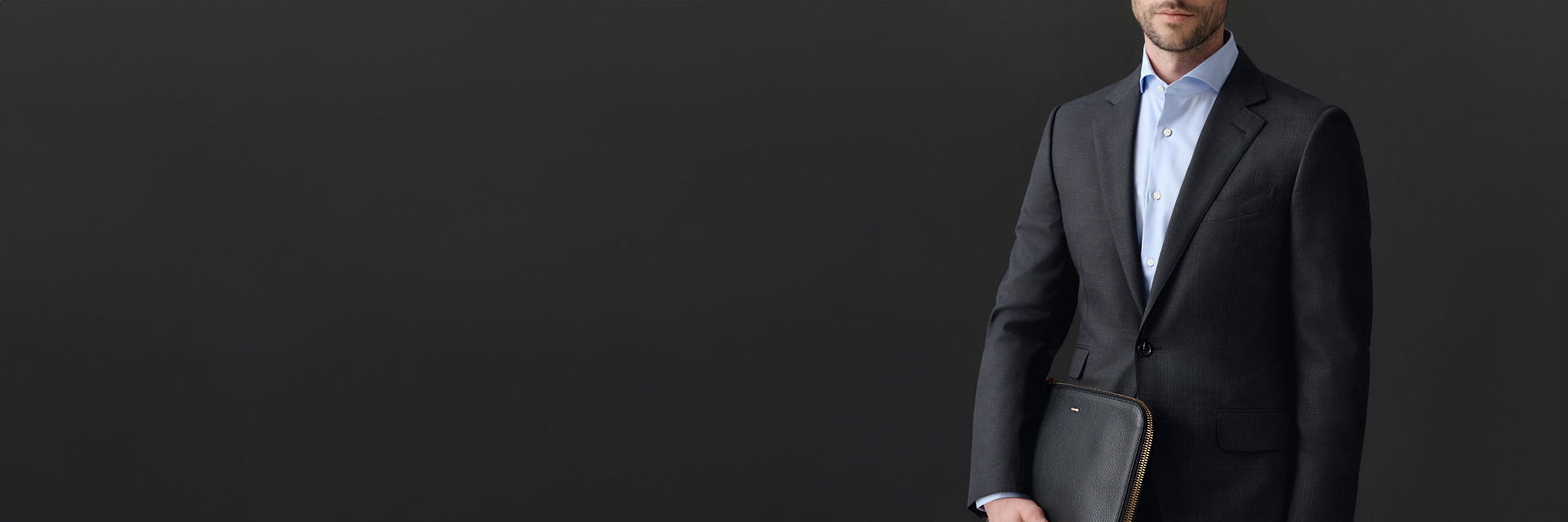 Detailansicht eines Herrenlooks mit Anzug in anthrazit, hellblauem Hemd und schwarzer Aktentasche Detailansicht eines Herrenlooks mit Anzug in anthrazit, hellblauem Hemd und schwarzer Aktentasche