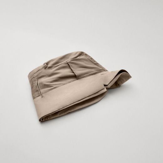 Beige Herrensakko, auf links gedreht und doppelt gefaltet, liegt flach auf hellem, neutralem Hintergrund.