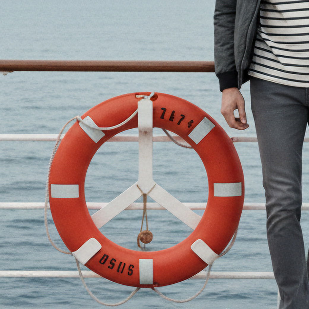 Rettungsring an Reling eines Schiffes, daneben ein Mann in grauer Jeans und gestreiftem Shirt, dahinter das Meer. Rettungsring an Reling eines Schiffes, daneben ein Mann in grauer Jeans und gestreiftem Shirt, dahinter das Meer.