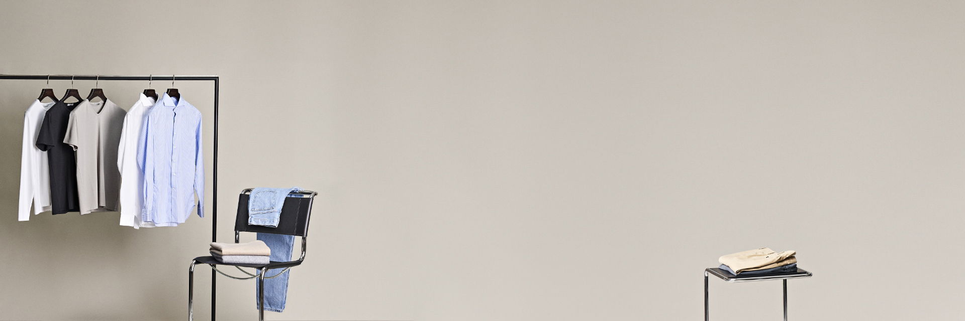 Gehängte und gelegte Teile einer Capsule Wardrobe auf Kleiderstange und Stuhl Gehängte und gelegte Teile einer Capsule Wardrobe auf Kleiderstange und Stuhl