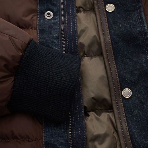 Nahaufnahme einer Herren-Daunen-Bomberjacke mit braunem Innenfutter, dunkelblauem Denim-Außenstoff, Reißverschluss und Knopfleiste. Nahaufnahme einer Herren-Daunen-Bomberjacke mit braunem Innenfutter, dunkelblauem Denim-Außenstoff, Reißverschluss und Knopfleiste.