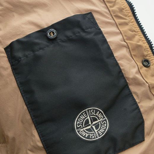 Beige-braune Herrenjacke mit schwarzer Innentasche, Druckknopfverschluss und weißem Stone Island Designerlogo. Beige-braune Herrenjacke mit schwarzer Innentasche, Druckknopfverschluss und weißem Stone Island Designerlogo.