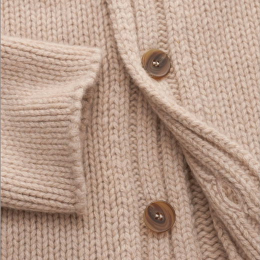 Beige Kaschmir-Cardigan mit geripptem Ärmelbündchen und braunen Knöpfen, Detailaufnahme der Strickstruktur. Beige Kaschmir-Cardigan mit geripptem Ärmelbündchen und braunen Knöpfen, Detailaufnahme der Strickstruktur.