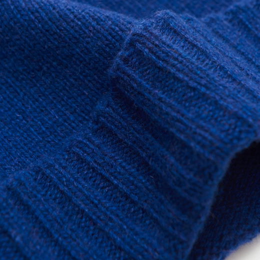 Blau gestrickter Ripp-Saum einer weichen Cashmere-Mütze, Detailaufnahme der feinen Maschenstruktur und Textur.