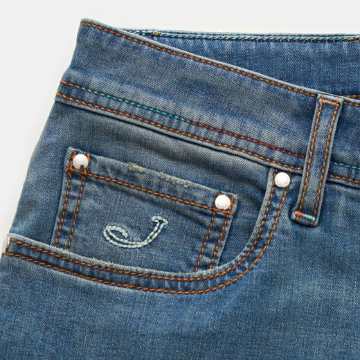 Jeans in Graublau mit kleiner bestickter Münztasche, orangeroten Nähten und silbernen Nieten, Detailansicht. Jeans in Graublau mit kleiner bestickter Münztasche, orangeroten Nähten und silbernen Nieten, Detailansicht.