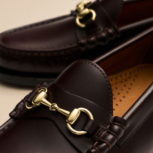 Braune Herren-Lederloafer mit goldener Schnalle, feiner Naht und gepolstertem Innenfutter, Nahaufnahme. Braune Herren-Lederloafer mit goldener Schnalle, feiner Naht und gepolstertem Innenfutter, Nahaufnahme.