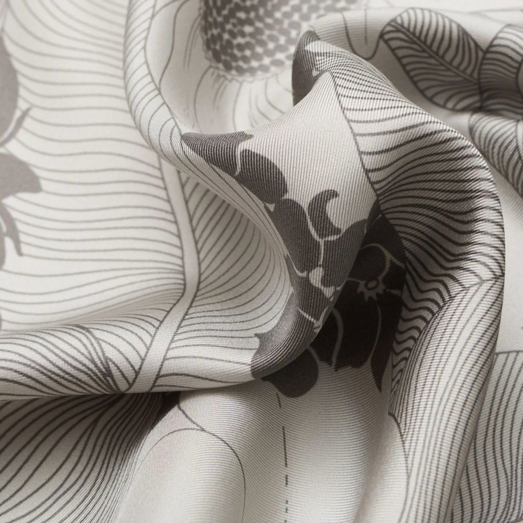 Cremefarbenes, gemustertes Seiden-Einstecktuch mit feinen braunen Linien und floralen Details, nah aufgenommen.