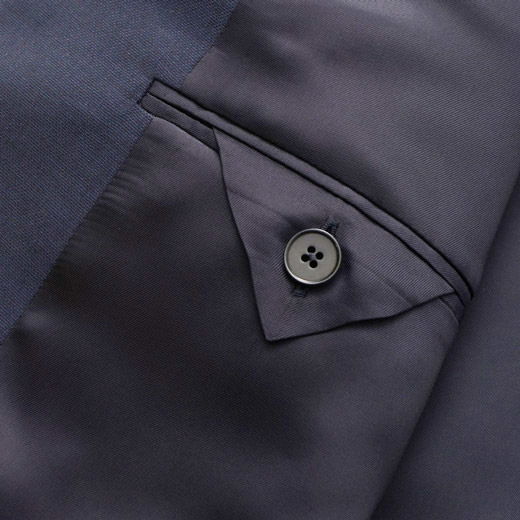 Detailaufnahme der Innenseite einer dunkelblauen Anzughose mit Knopfverschluss an einer kleinen Innentasche.