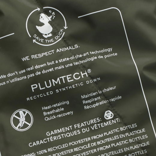 Detailaufnahme der Innenschrift einer olivgrünen Leichtdaunenjacke mit Infos zu PLUMTECH® recycelter synthetischer Daune. Detailaufnahme der Innenschrift einer olivgrünen Leichtdaunenjacke mit Infos zu PLUMTECH® recycelter synthetischer Daune.