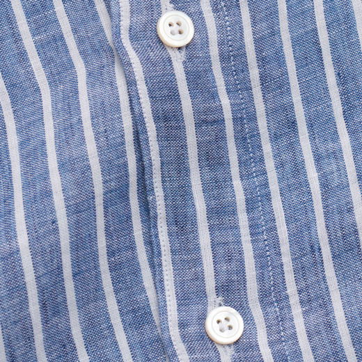 Detailaufnahme der Knopfleiste eines blau-weiß gestreiften Leinenhemdes mit zwei weißen Knöpfen und feiner Naht.