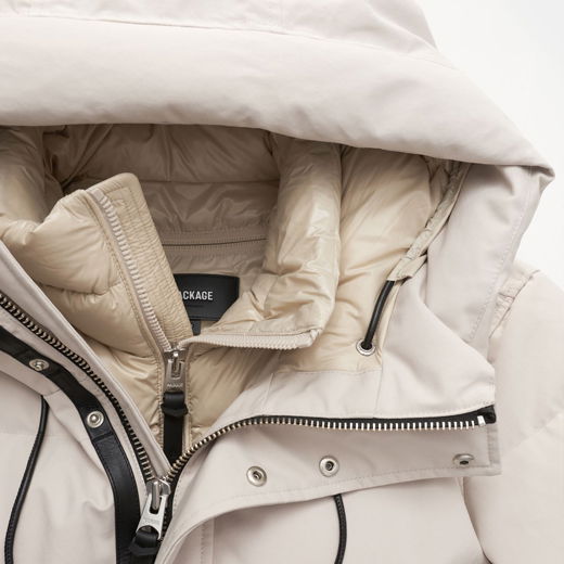 Detailaufnahme einer beige Daunenjacke mit Kapuze, Reißverschluss, Druckknöpfen und innenliegendem Steppfutter. Detailaufnahme einer beige Daunenjacke mit Kapuze, Reißverschluss, Druckknöpfen und innenliegendem Steppfutter.