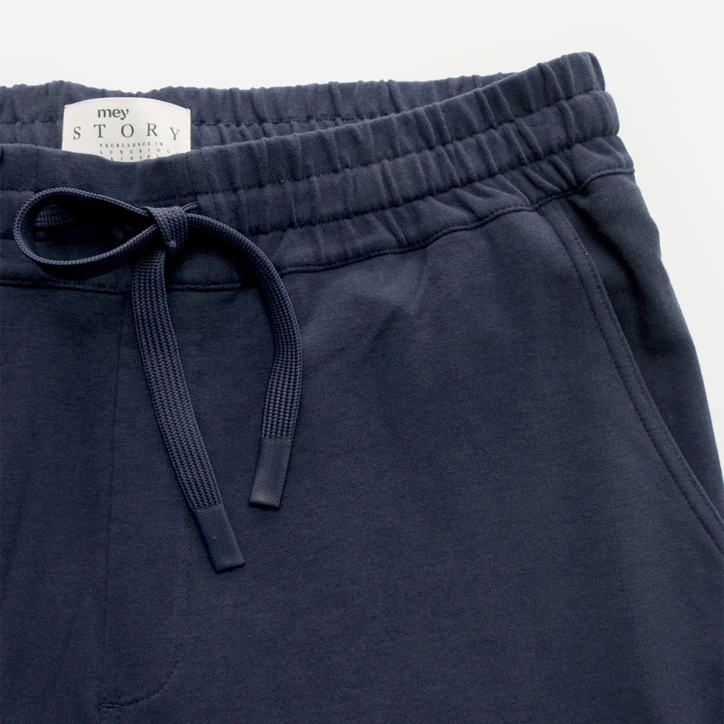 Dunkelblaue Joggpants mit elastischem Tunnelzug-Bund, sichtbarem Markenlabel und seitlicher Eingrifftasche, Detailansicht. Dunkelblaue Joggpants mit elastischem Tunnelzug-Bund, sichtbarem Markenlabel und seitlicher Eingrifftasche, Detailansicht.