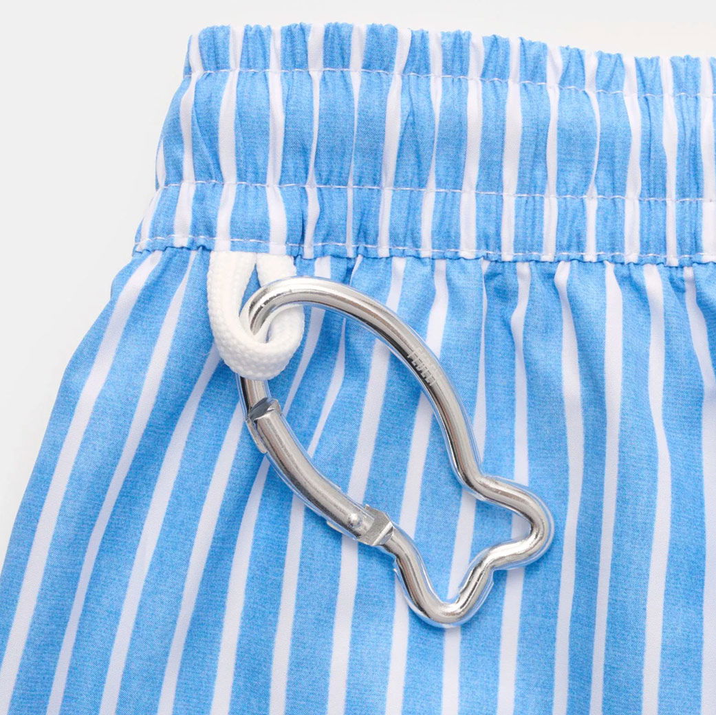 Blau-weiß gestreifte Badehose mit elastischem Bund und weißem Kordelzug, daran silberner Karabiner in Fischform.