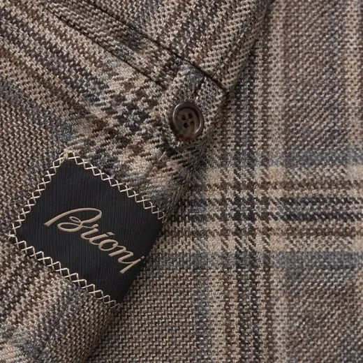Detailaufnahme des Innenstoffes eines Herren-Sakkos mit braunem Karomuster, Knopf und gesticktem Etikett 'Brioni'. Detailaufnahme des Innenstoffes eines Herren-Sakkos mit braunem Karomuster, Knopf und gesticktem Etikett 'Brioni'.