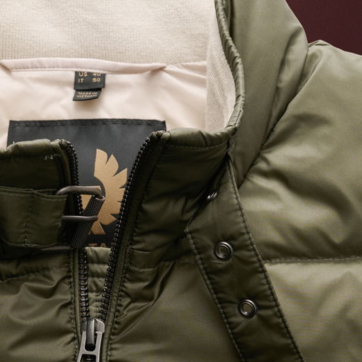 Detailaufnahme des olivgrünen Kragens einer Daunenweste mit geöffneter Schnalle, Reißverschluss und Innenfutter.