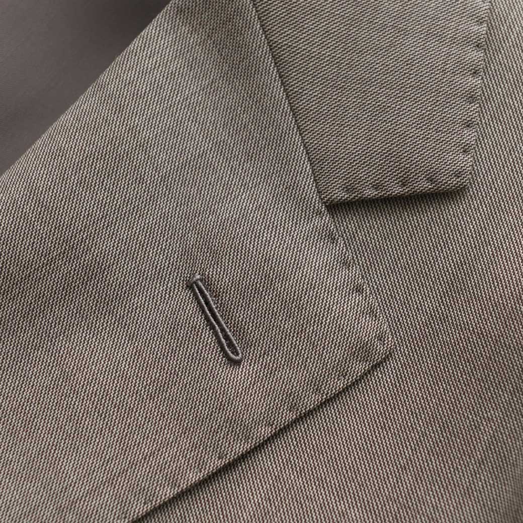 Detailaufnahme des Kragens eines grauen Herren-Sakkos mit feiner Gewebestruktur und Knopfloch am Revers.