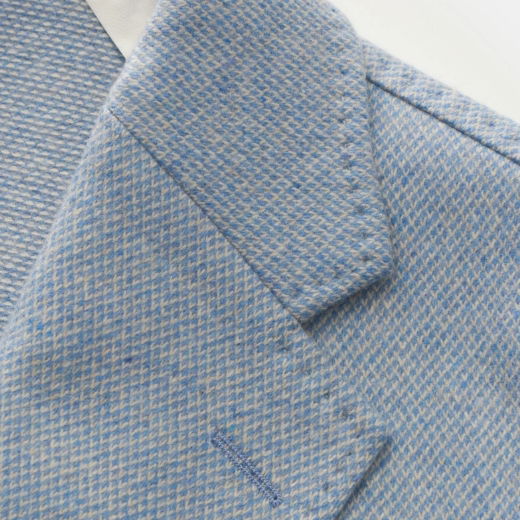 Detailaufnahme des hellblauen Herren-Sakko-Kragens mit feinem Muster und leichter Stoffstruktur. Detailaufnahme des hellblauen Herren-Sakko-Kragens mit feinem Muster und leichter Stoffstruktur.