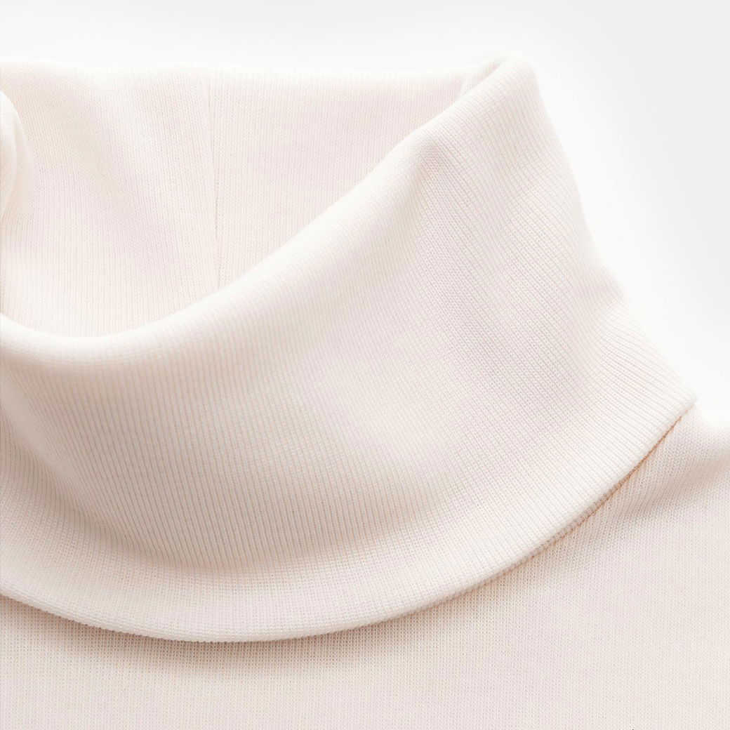 Detailaufnahme des weißen, feinstrukturierten Rollkragens eines Herrenpullover aus weichem Stoff.
