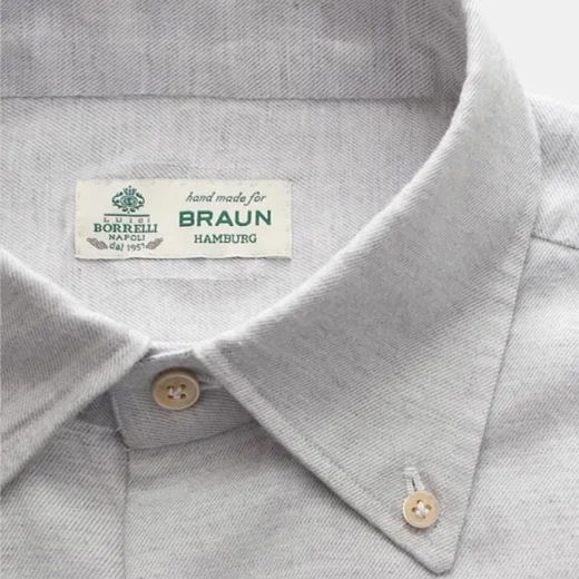 Detailaufnahme eines hellgrauen Herrenhemd-Kragens mit Knöpfen und einem Label „Luigi Borrelli Napoli hand made for Braun Hamburg“. Detailaufnahme eines hellgrauen Herrenhemd-Kragens mit Knöpfen und einem Label „Luigi Borrelli Napoli hand made for Braun Hamburg“.