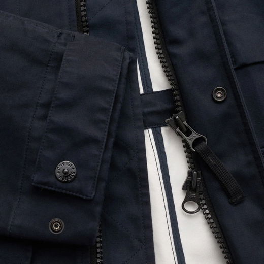 Detailaufnahme eines dunkelblauen Herrenjacken-Ärmels mit Reißverschluss, Druckknopf und sichtbarem Innenfutter.