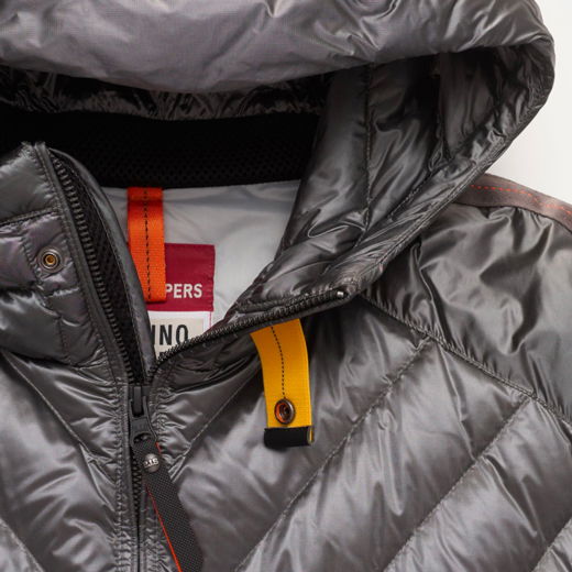 Detailaufnahme eines grau-silbernen Daunenjacken-Reißverschlusses mit gelber Lasche und roten Nähten am Kragen. Detailaufnahme eines grau-silbernen Daunenjacken-Reißverschlusses mit gelber Lasche und roten Nähten am Kragen.