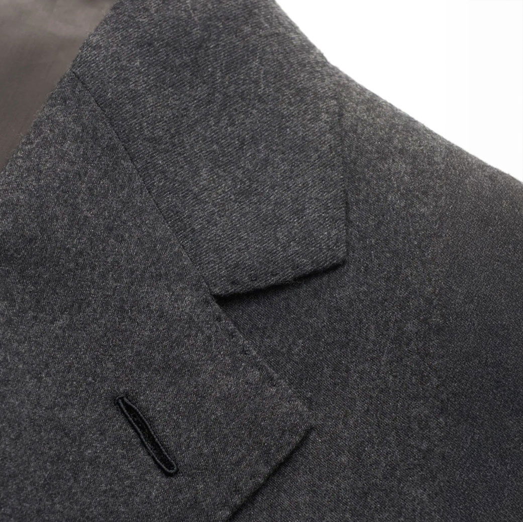 Detaillierte Nahaufnahme des Revers und der Schulterpartie eines anthrazitfarbenen Herren-Sakkos aus feinem Stoff. Detaillierte Nahaufnahme des Revers und der Schulterpartie eines anthrazitfarbenen Herren-Sakkos aus feinem Stoff.