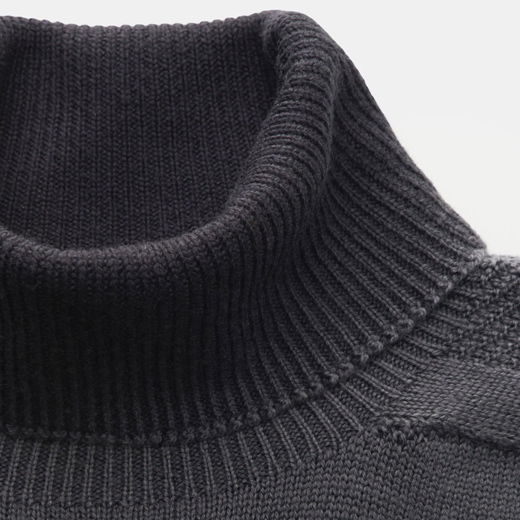Detailaufnahme eines dunkelgrauen, fein gestrickten Herren-Rollkragenpullovers mit geripptem Kragen und Schulterbereich. Detailaufnahme eines dunkelgrauen, fein gestrickten Herren-Rollkragenpullovers mit geripptem Kragen und Schulterbereich.