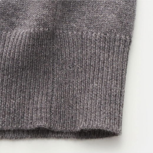 Detailaufnahme des grauen Saums eines Herrenpullunders aus feinem, weichem Strickmaterial mit feiner Maschenstruktur. Detailaufnahme des grauen Saums eines Herrenpullunders aus feinem, weichem Strickmaterial mit feiner Maschenstruktur.