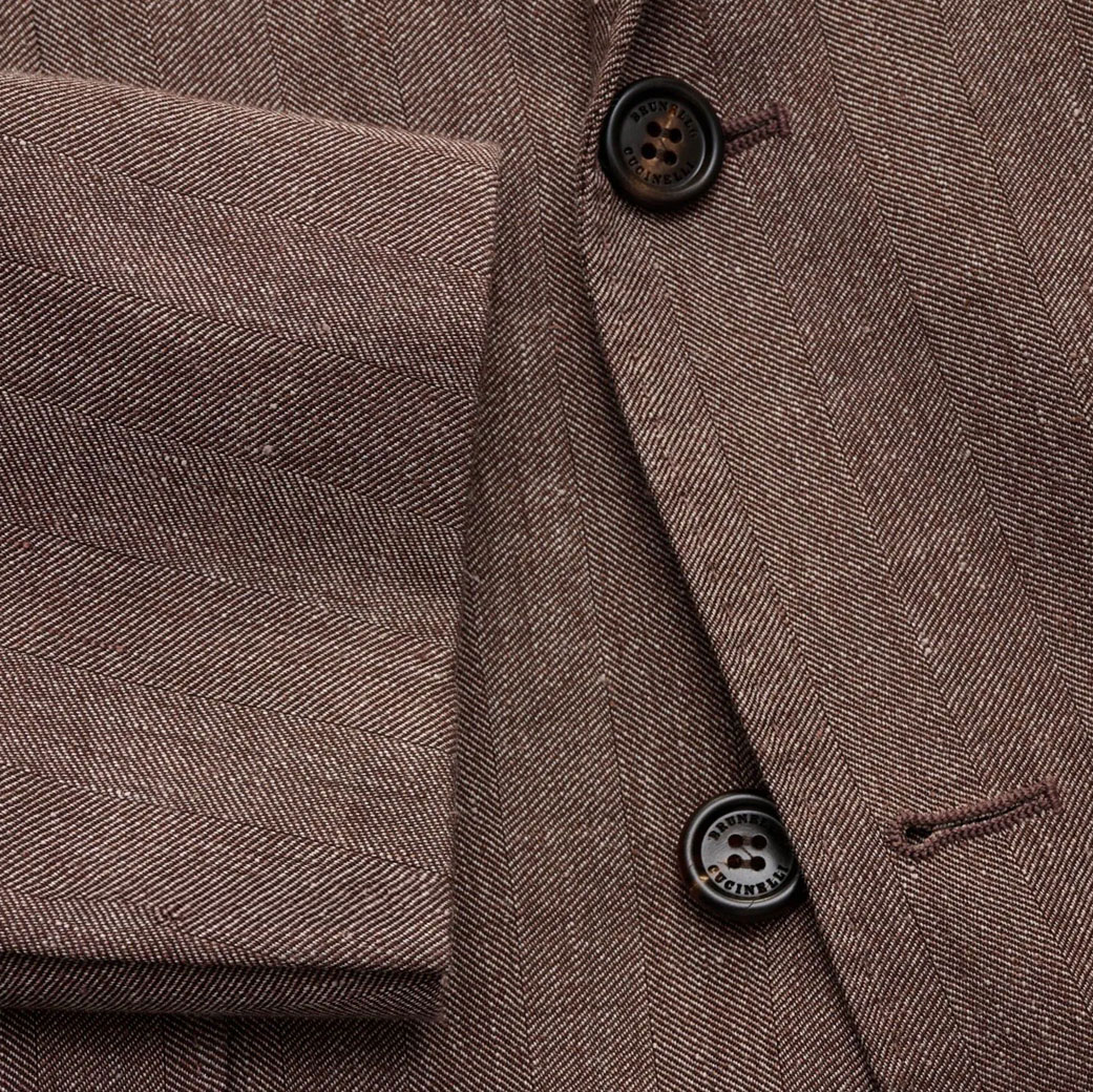 Detailaufnahme eines graubraunen Leinensakkos für Herren mit Fischgrätmuster, Knöpfen und Taschenklappe.