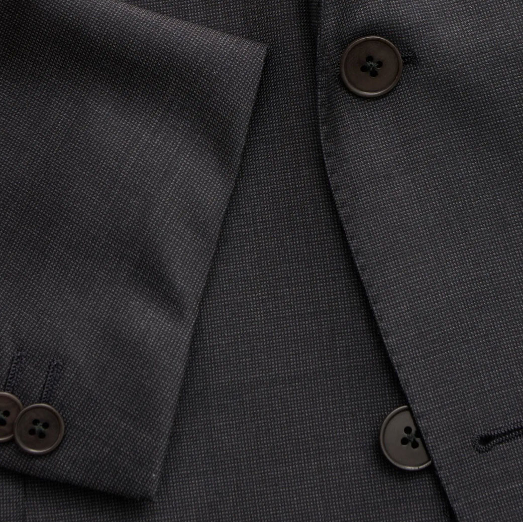 Detailaufnahme eines dunkelgrauen Merinowoll-Sakkos mit feiner Struktur und braunen Knöpfen an Ärmel und Vorderseite.