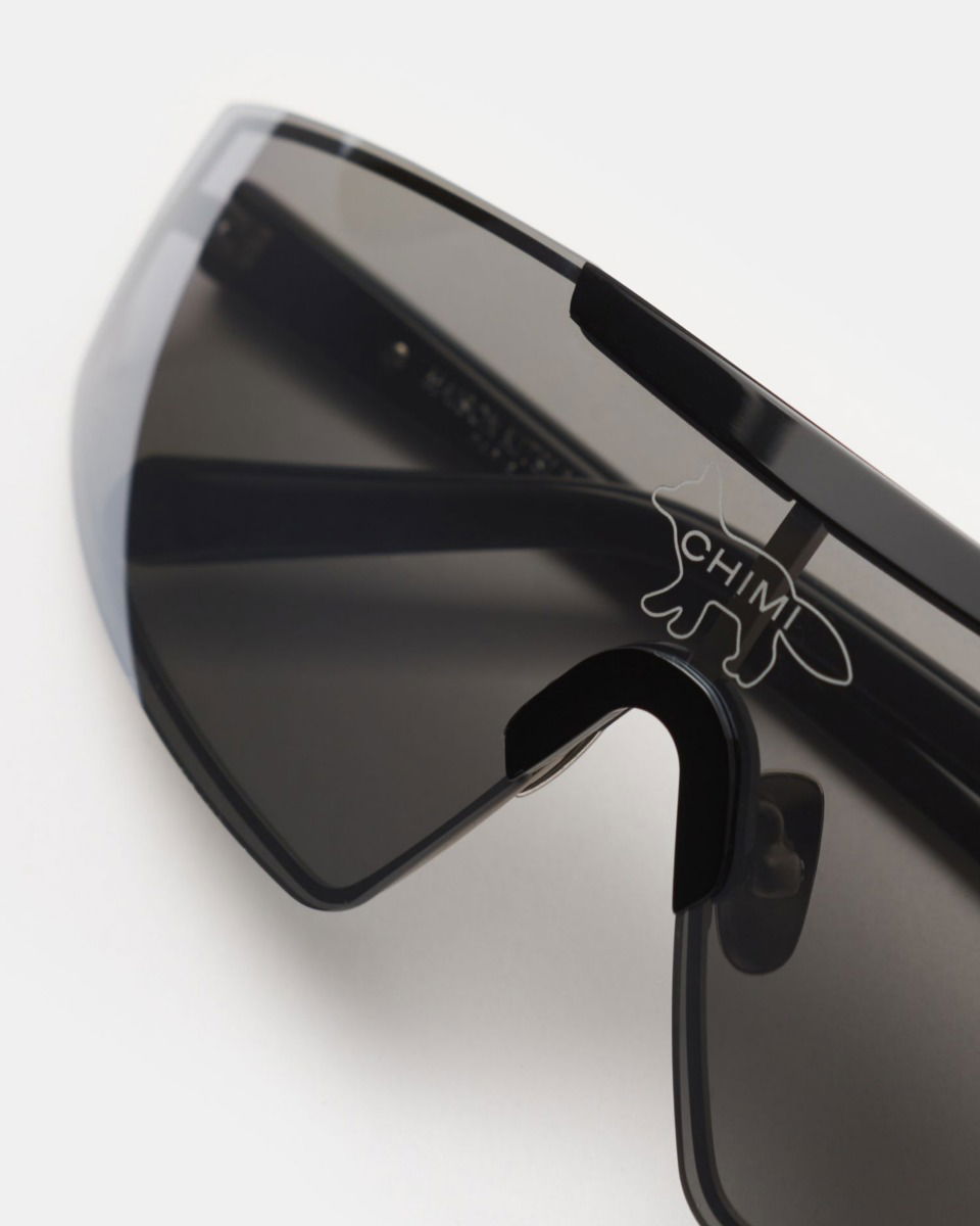 Schwarze Radsport-Sonnenbrille mit durchgehendem dunklem Visier und transparentem Logo in Form eines Tieres mit Schriftzug CHMI.