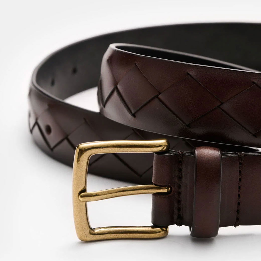 Brauner Leder-Gürtel mit geflochtenem Muster und goldfarbener Metallschnalle, auf weißem Hintergrund.