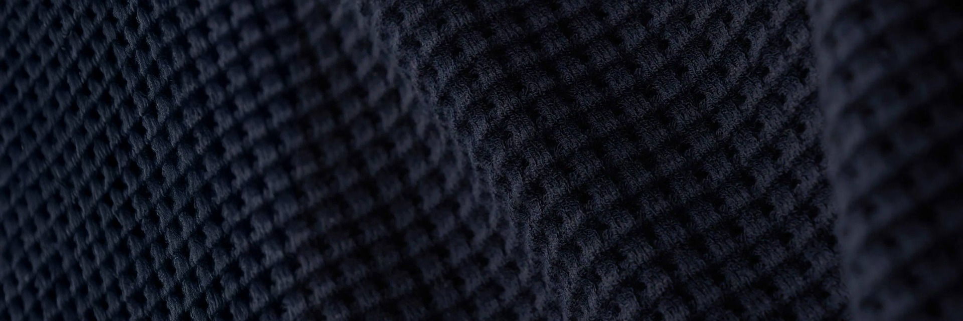 Detailaufnahme eines navyblauen Viskosestoffes mit strukturierter, wabenförmiger Waffelstruktur und feiner Webart. Detailaufnahme eines navyblauen Viskosestoffes mit strukturierter, wabenförmiger Waffelstruktur und feiner Webart.