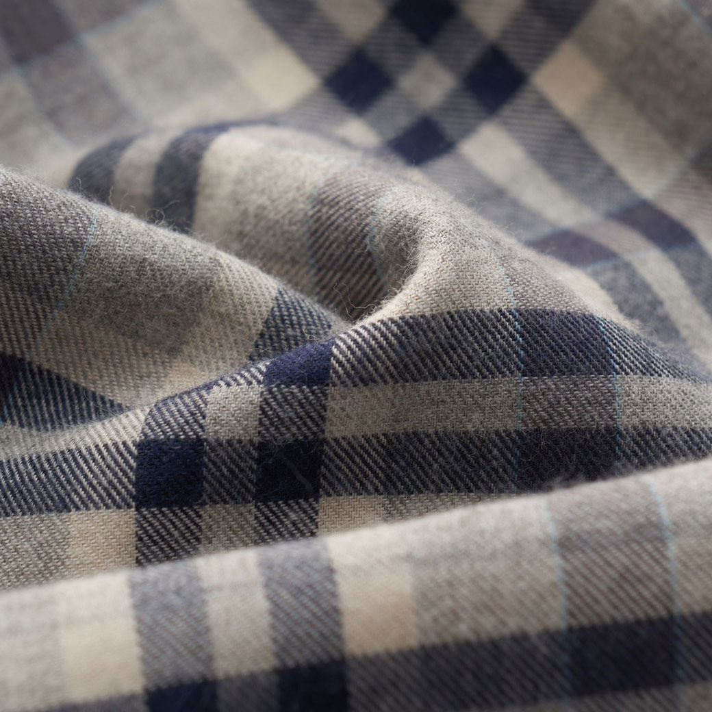 Beige-blau kariertes Flanellstoff-Muster in Nahaufnahme mit weicher, leicht gewellter Textur und feinen Fasern.