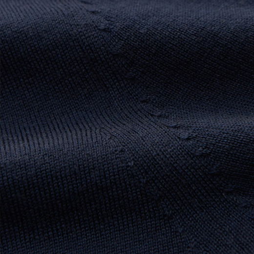 Detailaufnahme eines dunkelblauen Merinowolle-Pullovers mit feiner, gleichmäßiger Strickstruktur und sichtbaren Nahtlinien.