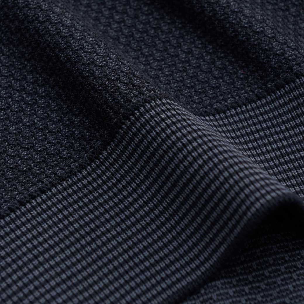 Dunkelblauer Herrenstoff mit zwei verschiedenen Texturen, eine grob gewoben und eine fein kariert, in Nahaufnahme.