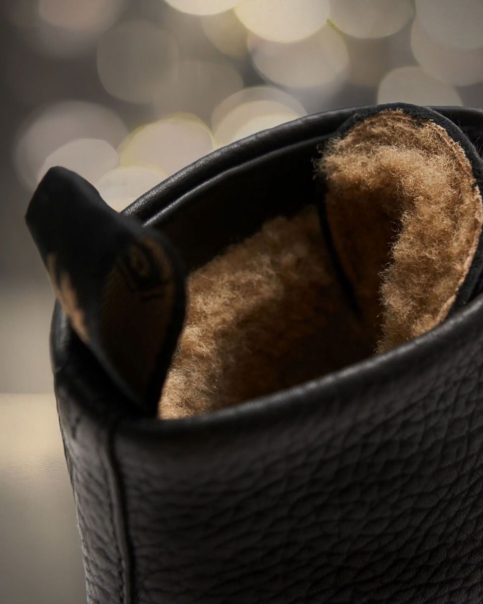 Detailansicht eines dunkelbraunen Lederboots für Herren mit warmem, hellbraunem Fellfutter und geriffelter Außenstruktur. Detailansicht eines dunkelbraunen Lederboots für Herren mit warmem, hellbraunem Fellfutter und geriffelter Außenstruktur.