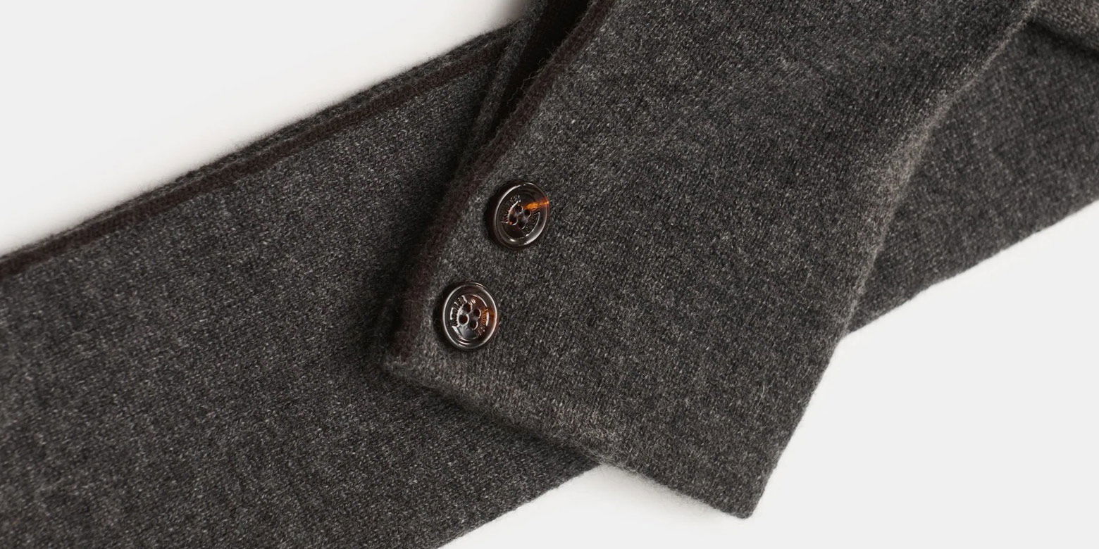 Anthrazitfarbener Herrenschal aus weichem Strick mit zwei braunen Knöpfen zur Fixierung des Schals.