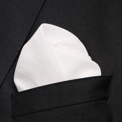 Weißes Einstecktuch aus Stoff, elegant gefaltet in der Brusttasche eines schwarzen Sakkos, Nahaufnahme.