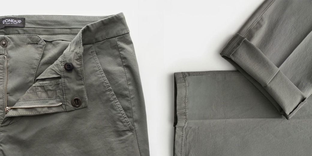 Detailaufnahme einer geöffneten grauen Herren-Baumwollhose mit sichtbarem Reißverschluss, Knöpfen und Beinabschluss.