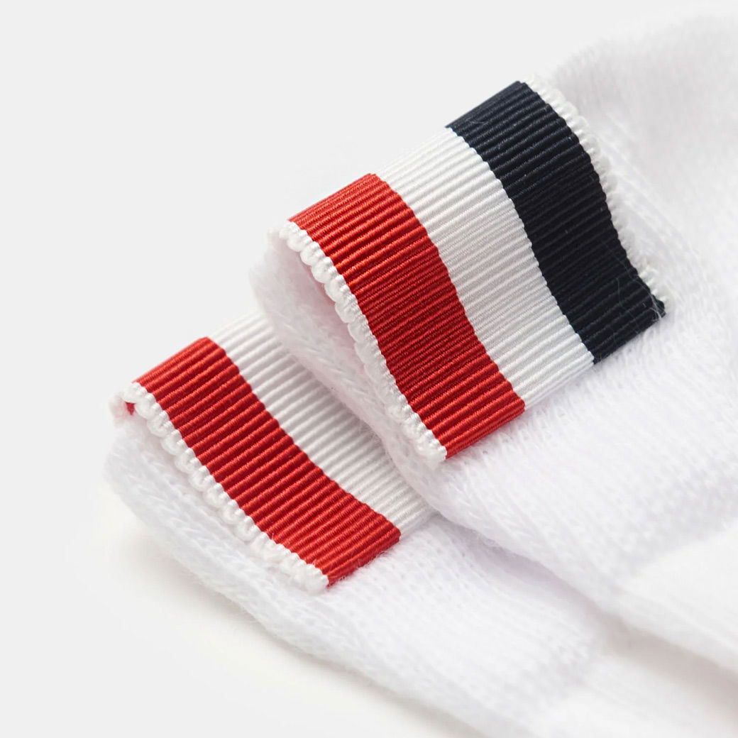 Weißer Herrenstrumpf mit kontrastierenden Rippstreifen in Rot, Weiß und Dunkelblau, detailreiche Nahaufnahme. Weißer Herrenstrumpf mit kontrastierenden Rippstreifen in Rot, Weiß und Dunkelblau, detailreiche Nahaufnahme.