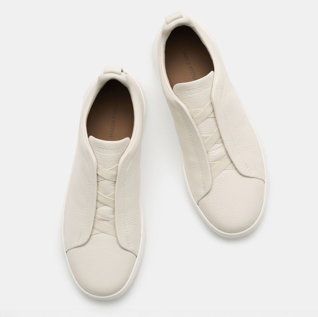 Ein Paar weiße Herren-Ledersneaker mit elastischen Schnürsenkeln, aus der Vogelperspektive auf weißem Hintergrund.